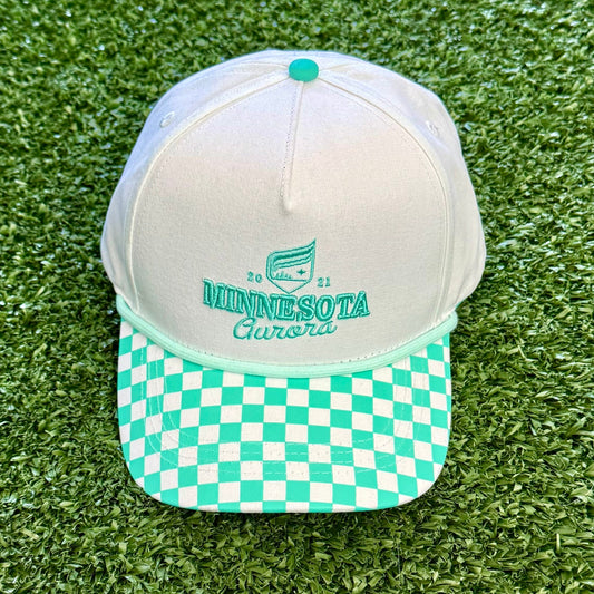 White and teal checkered cap on a green grass-like surface