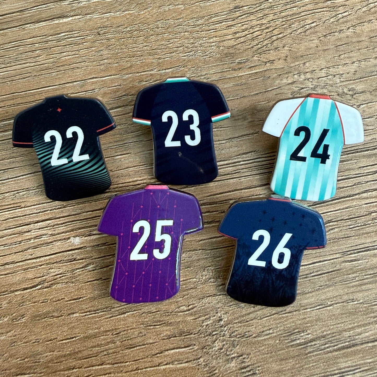 5 pins that look like soccer jerseys with numbers on them for each year