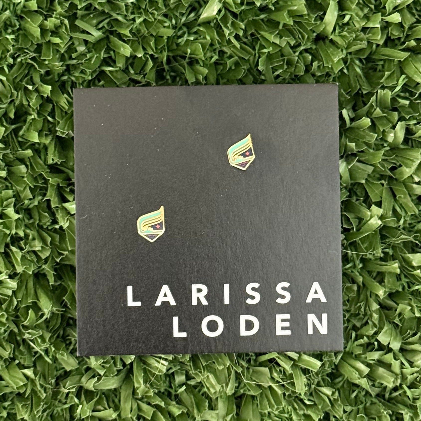 Larissa Loden card with earrings on a green grass background