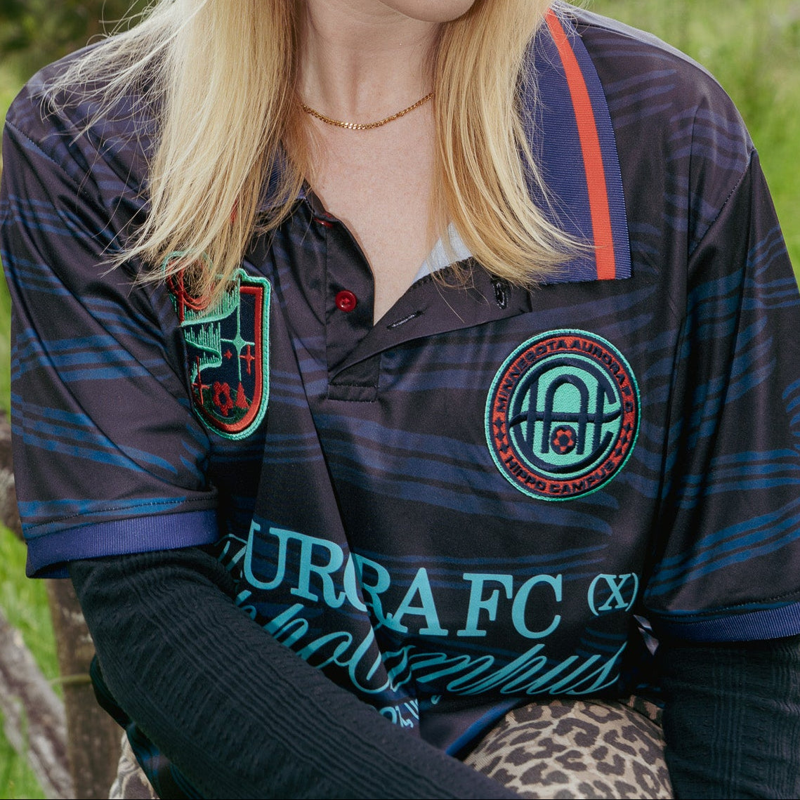 Person wearing a black cap and striped shirt with logos outdoors