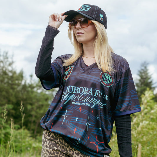 Woman wearing a patterned shirt and leopard print shorts in a grassy outdoor setting