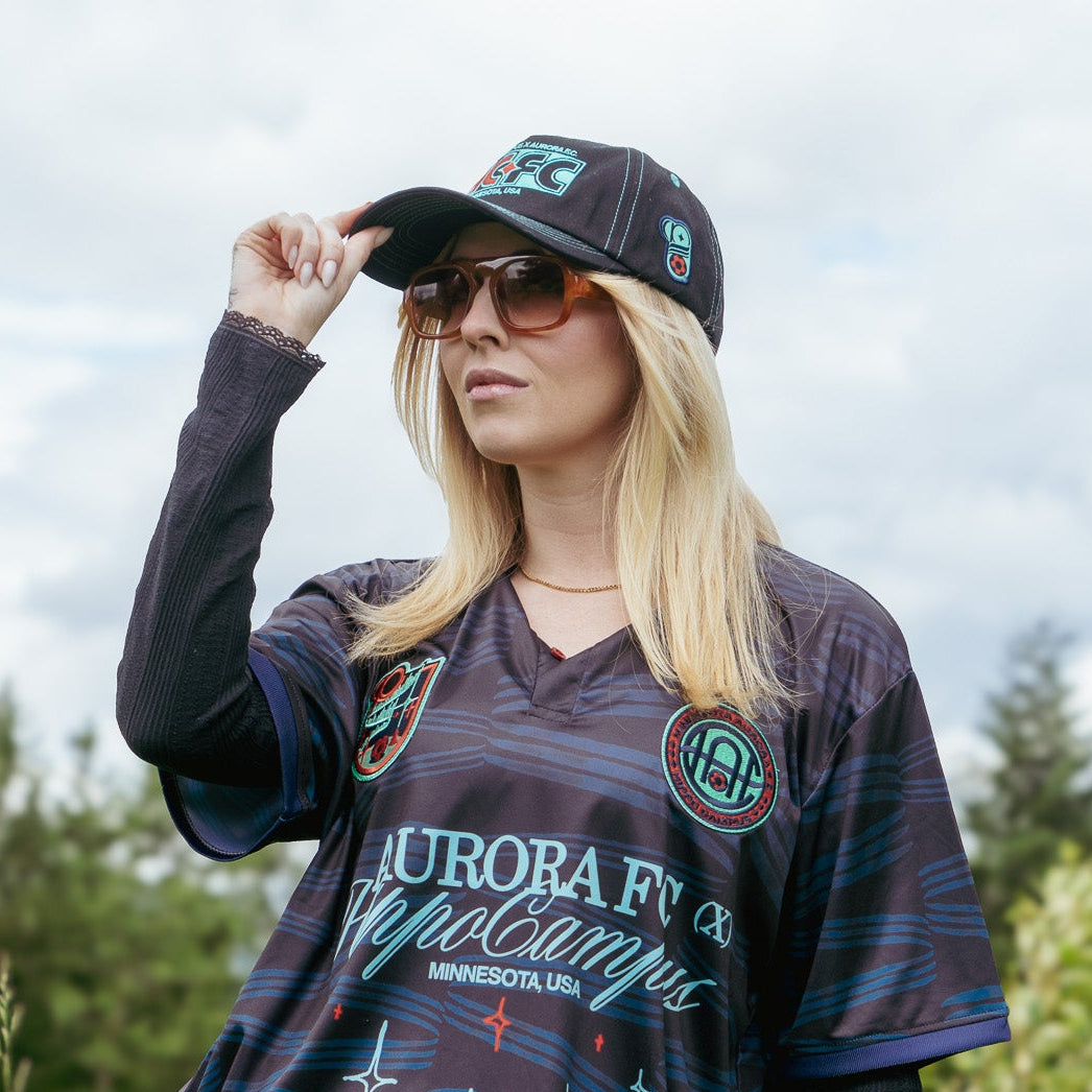 Woman wearing a patterned shirt and leopard print shorts in a grassy outdoor setting