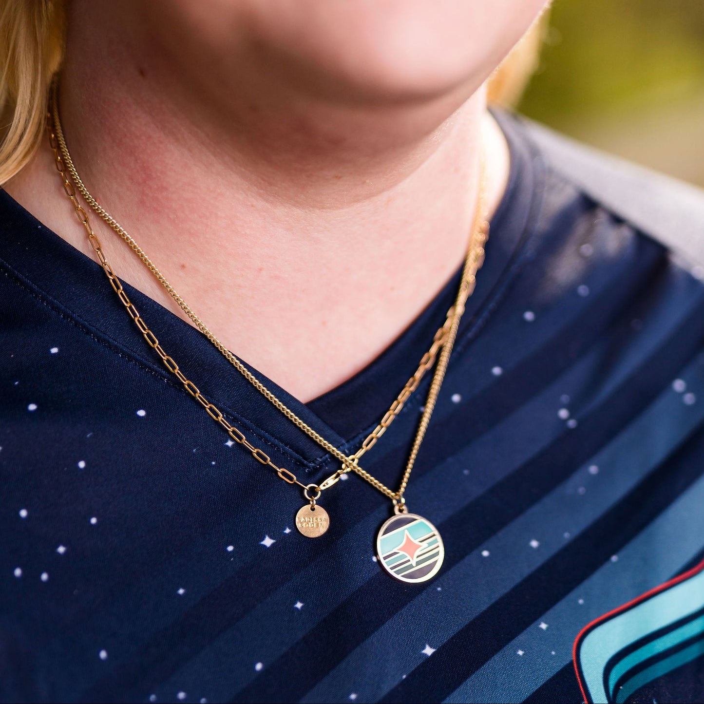 Person wearing a dark blue sports jersey and layered gold necklaces