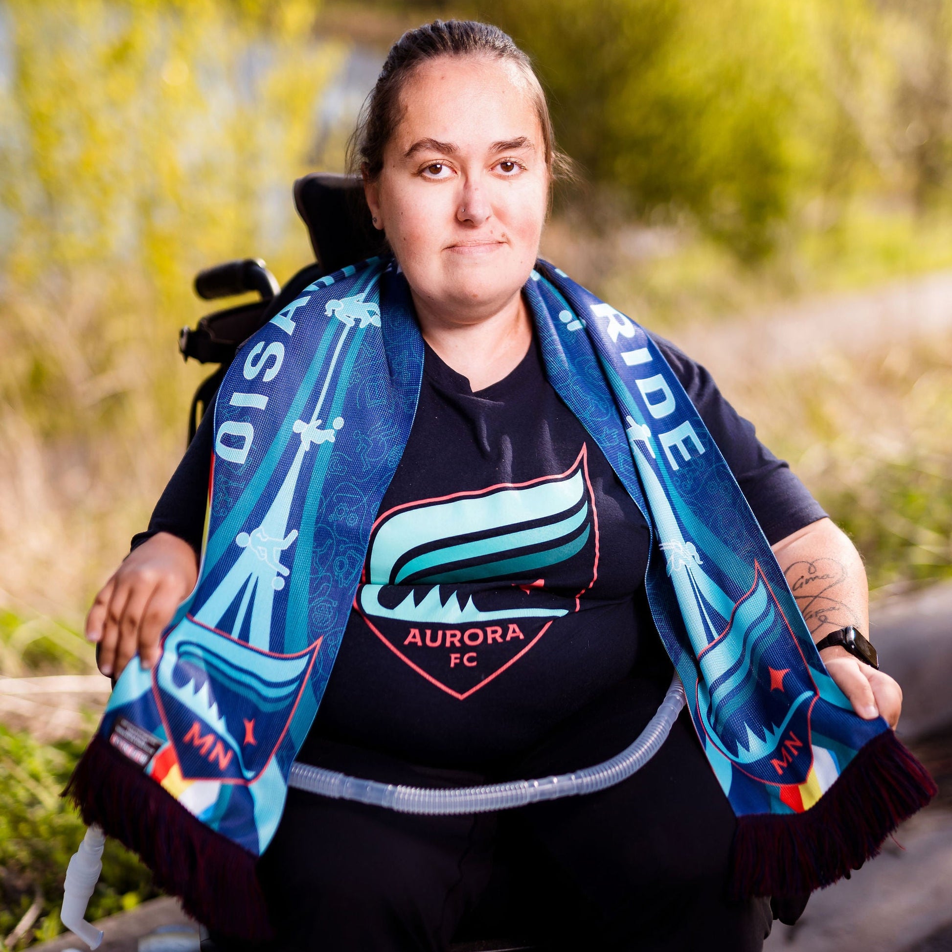 Person in a wheelchair wearing a disability scarf outdoors.