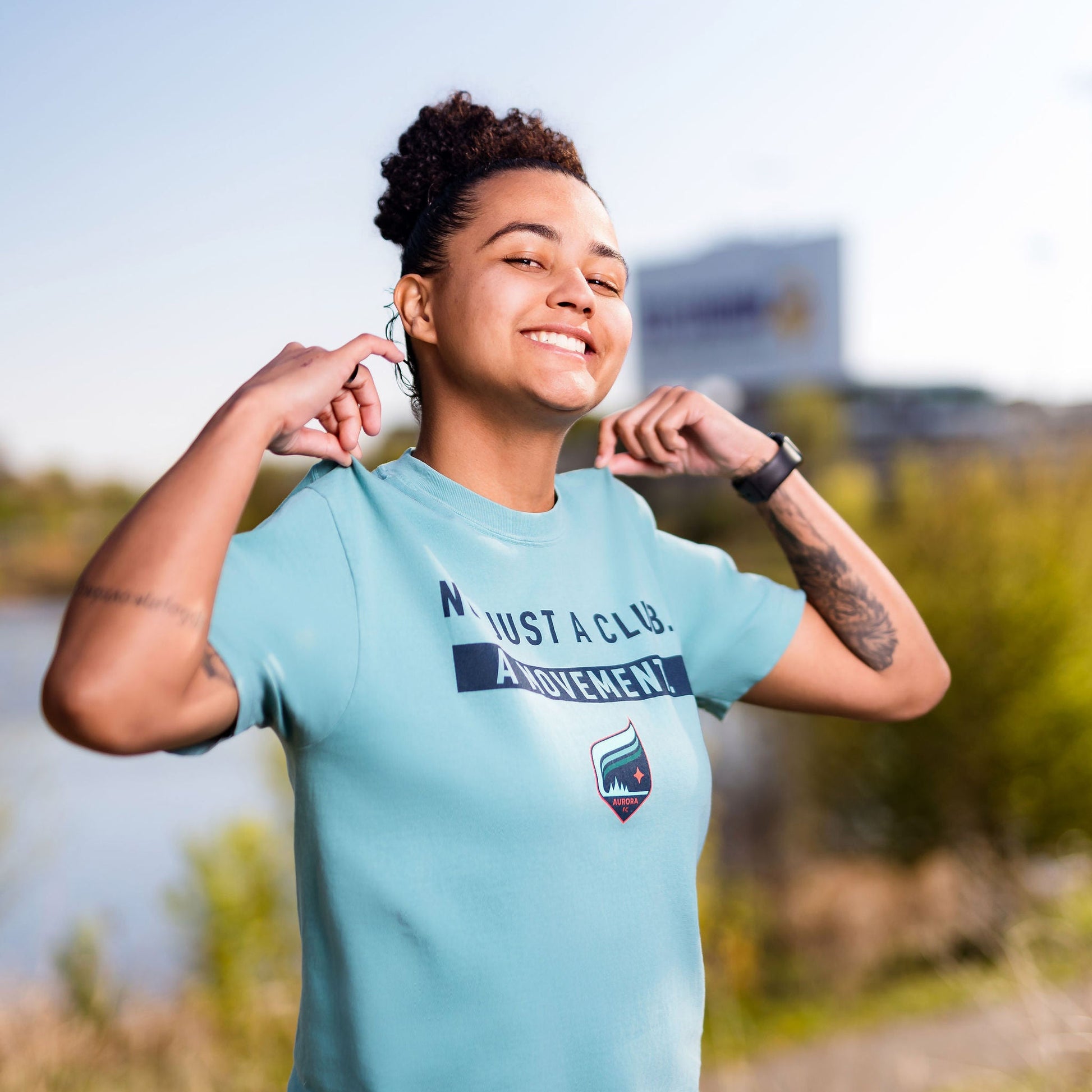 Person wearing a teal t-shirt with text and graphics outdoors