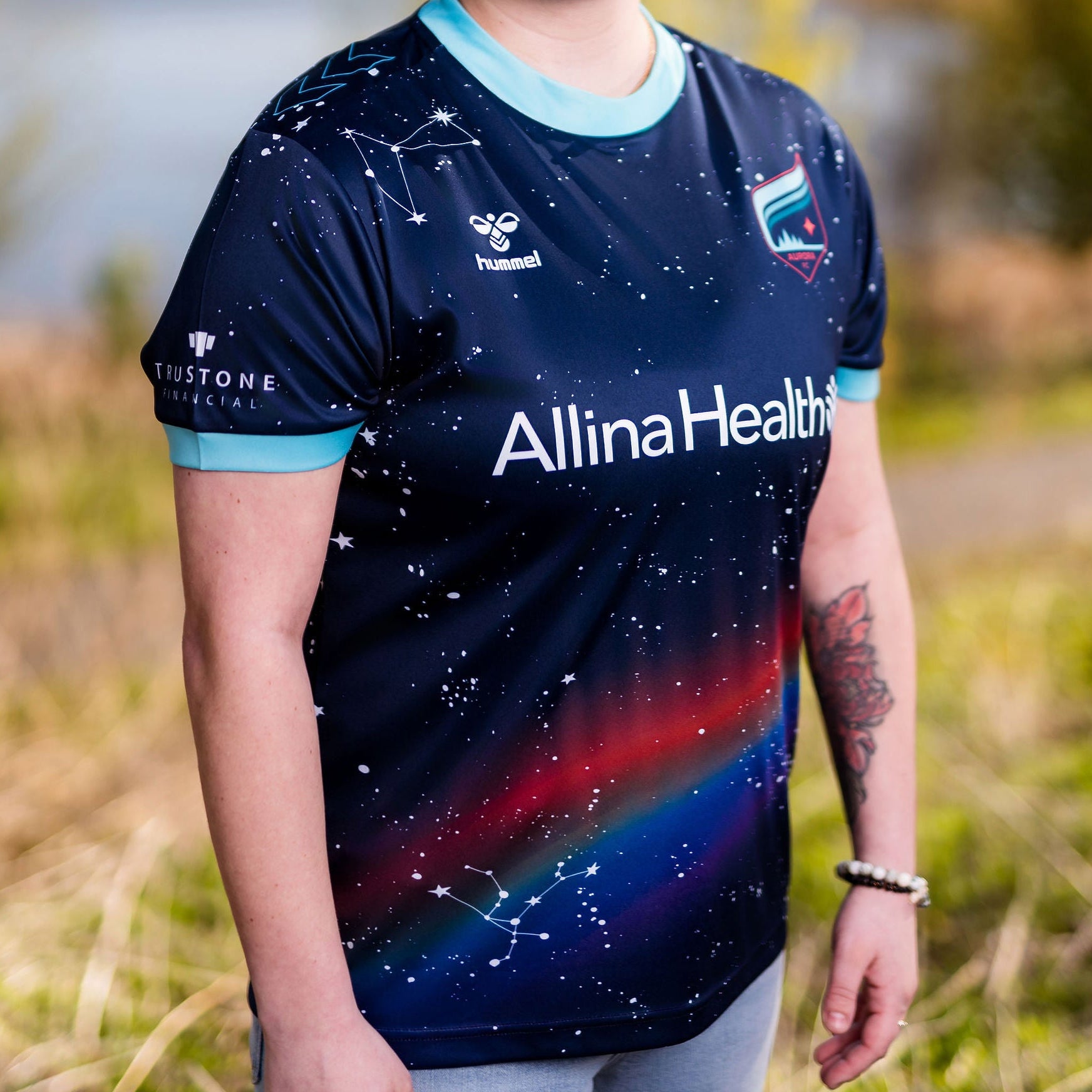 Person wearing a sports jersey with 'Allina Health' branding outdoors.