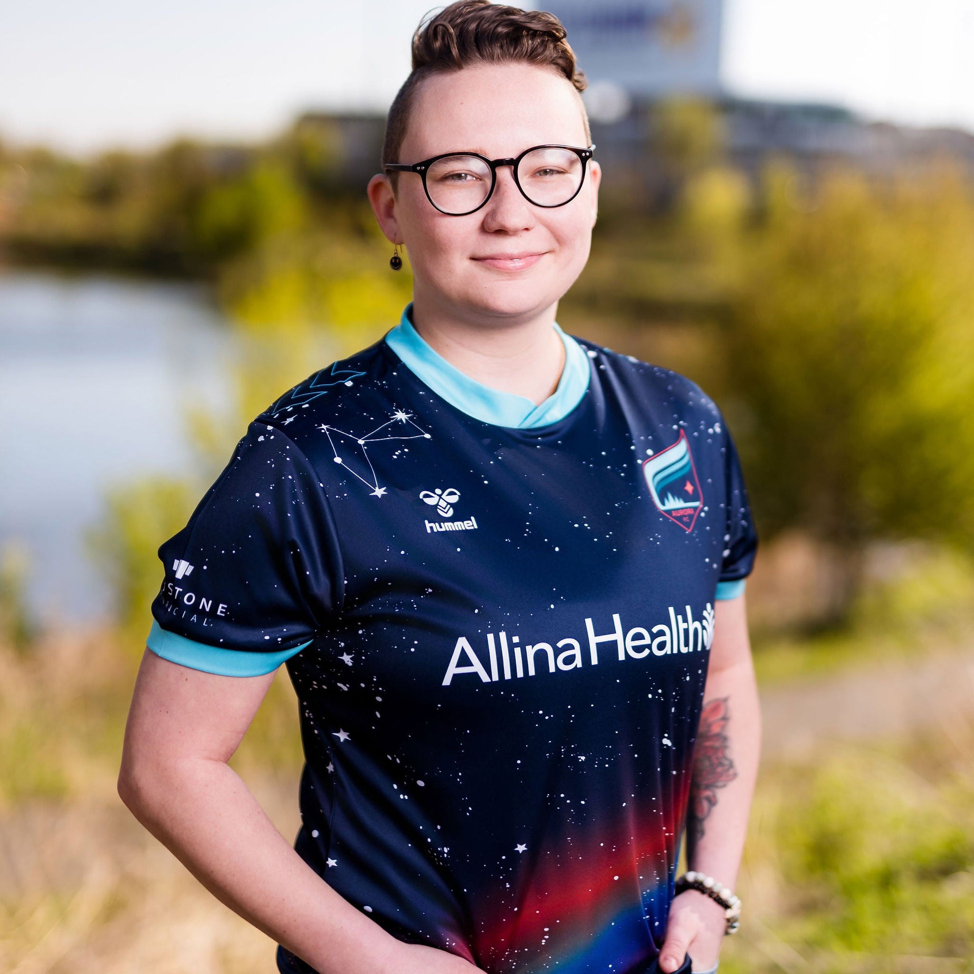 Person wearing a sports jersey with 'Allina Health' branding outdoors.