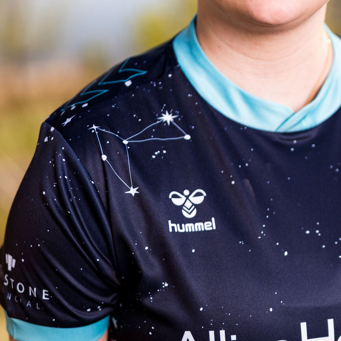 Person wearing a sports jersey with visible branding in an outdoor setting