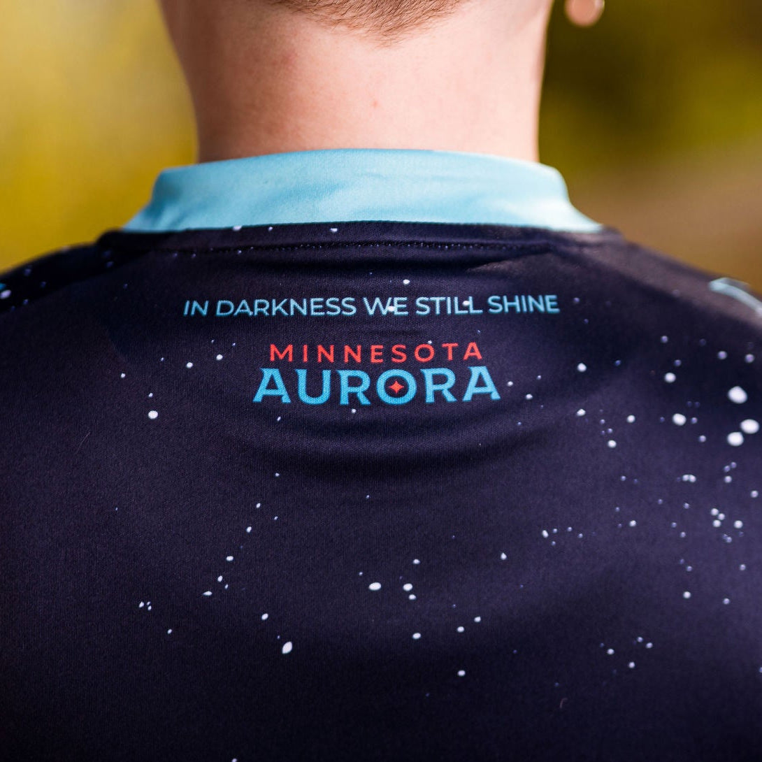 Person wearing a navy sports jersey with 'Minnesota Aurora' text on the back, blurred natural background