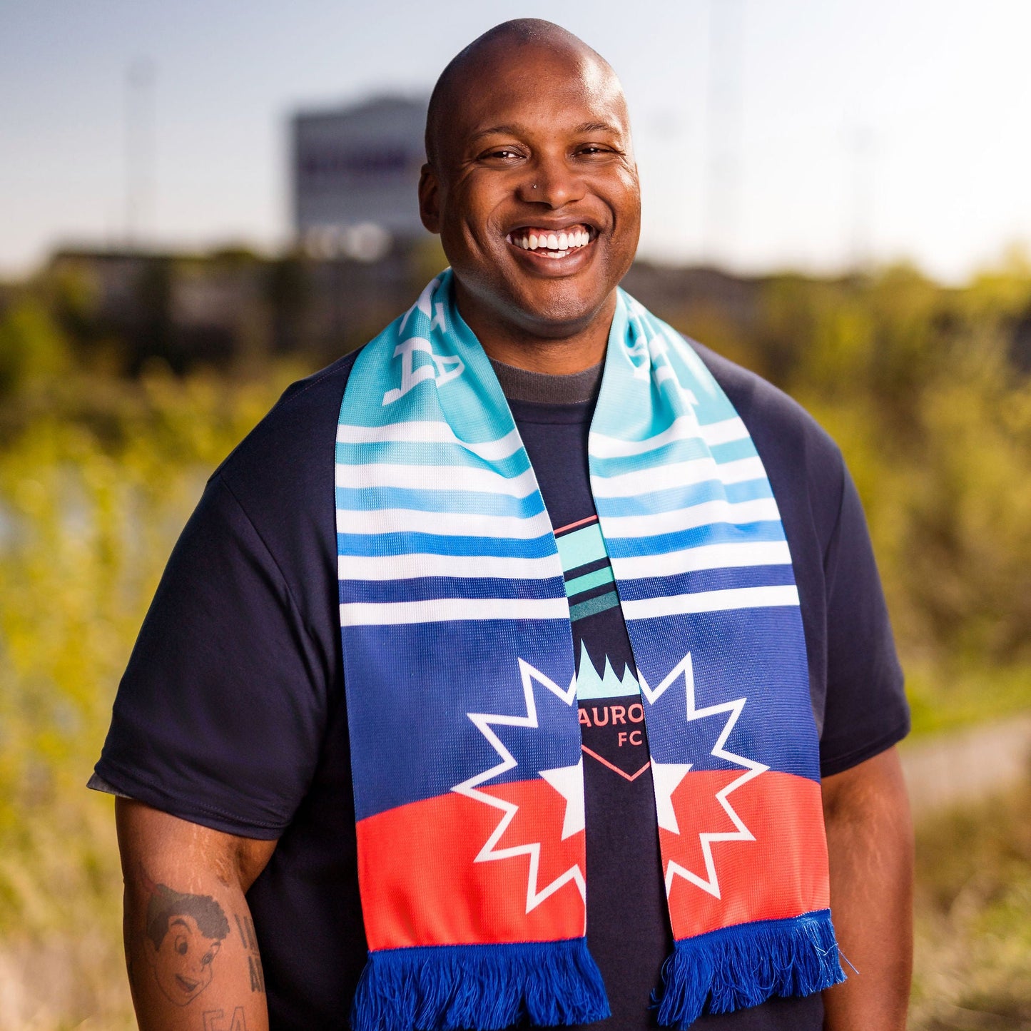 Man wearing a sports team scarf with a logo in an outdoor setting