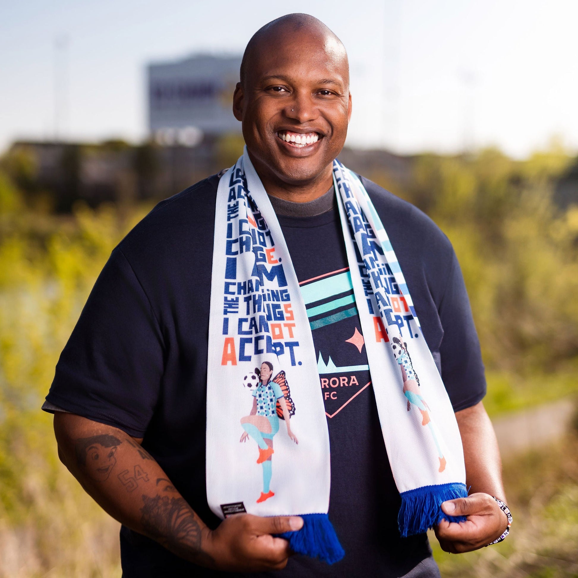 Man holding a colorful scarf with text and graphics outdoors