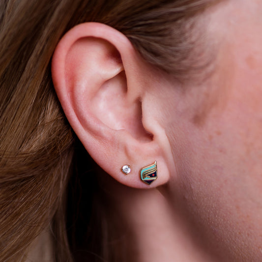 Close-up of an ear wearing two earrings with a blurred background